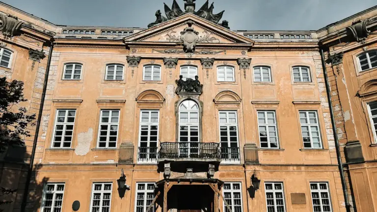 Historyczny, ozdobny żółty pałac z wieloma oknami w słoneczny, jesienny dzień w Polsce.