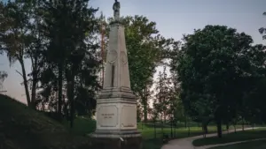 Kamienny pomnik na postumencie w otoczeniu drzew w bydgoskim parku w świetle dziennym.