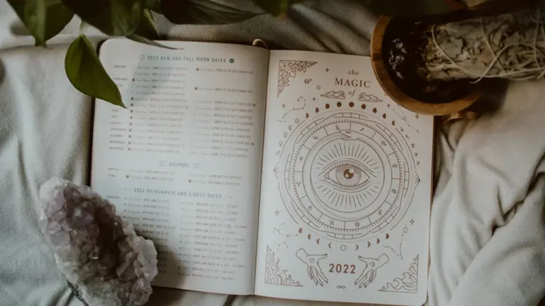 Otwarty kalendarz z motywami astrologicznymi, kryształem i kojącą atmosferą do codziennych przemyśleń.