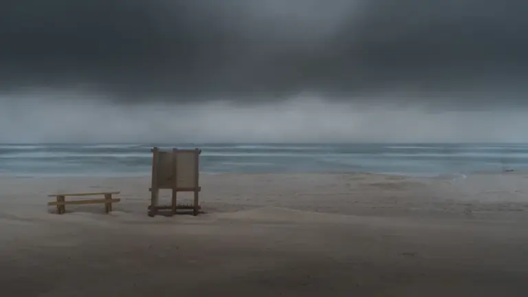Pusta plaża z kabiną pod ciemnym, burzowym niebem w pochmurny jesienny dzień.