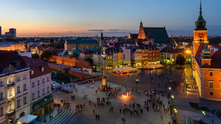 Panoramiczne ujęcie Zamku Królewskiego i odrestaurowanej warszawskiej Starówki o zachodzie słońca.